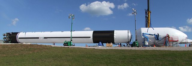 Side view of the whole Falcon 9 laid out horizontally on the slab at the Cape: engines, skirt, tank, interstage, second stage and fairing.