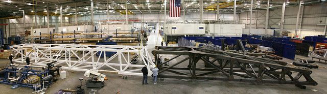 The aluminum and steel sections of the Falcon 9 erector laid along the Hawthorne factory floor.