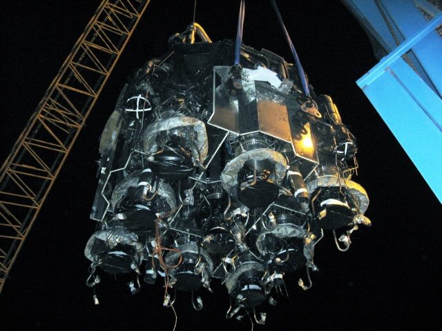 The Falcon 9 thrust structure with nine Merlin engines, lowered by crane from the test stand at McGregor.