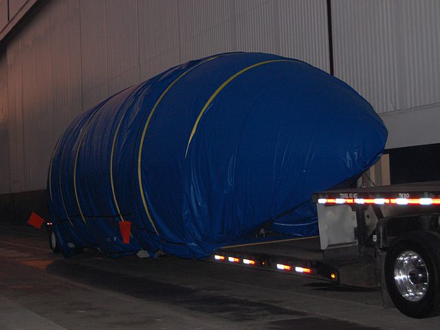 Half of the Falcon 9 payload fairing on a flatbed truck outside SpaceX headquarters.