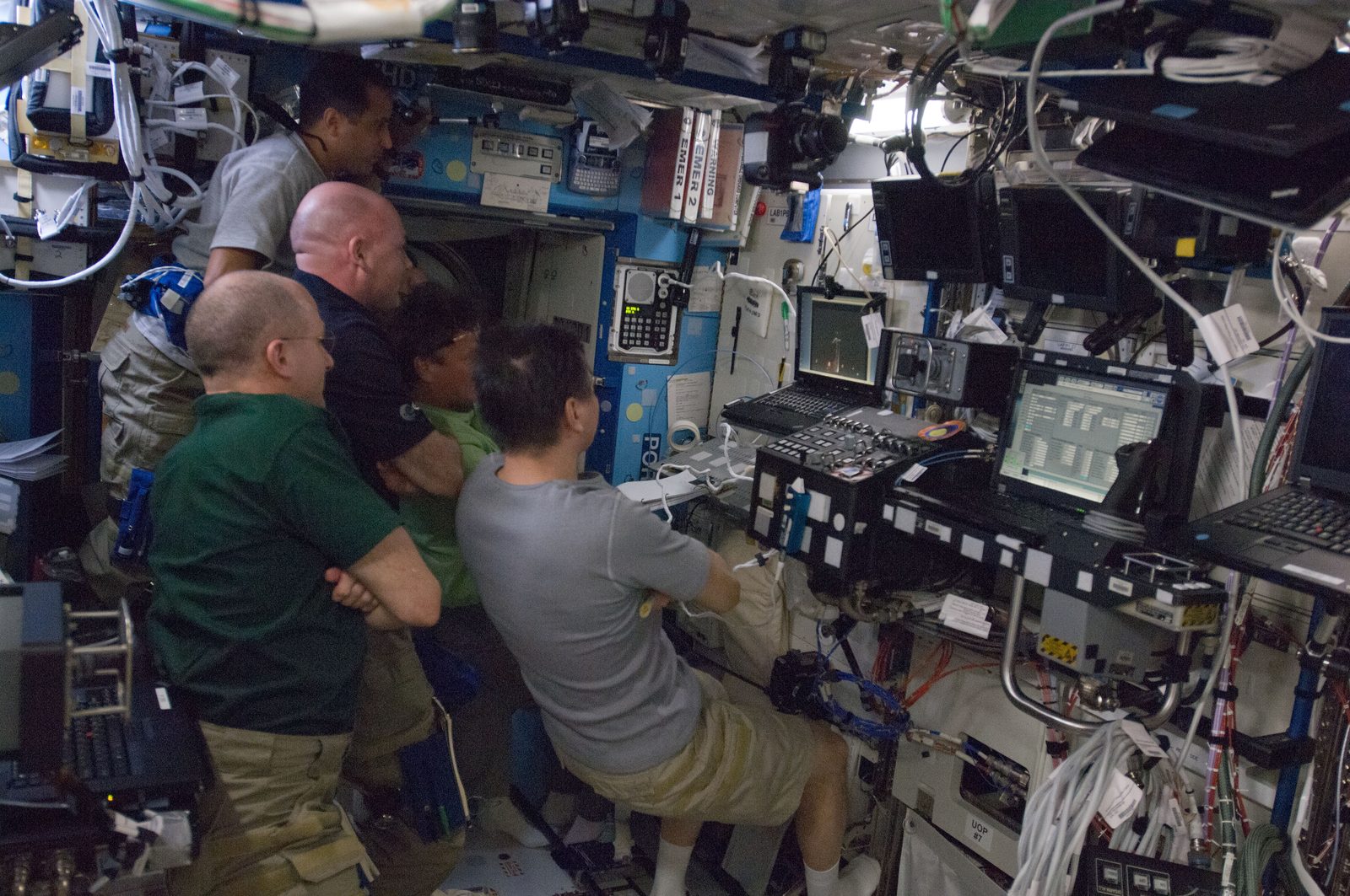 Expedition 31 crew members crowd around a laptop in the station's Destiny lab to watch the launch.